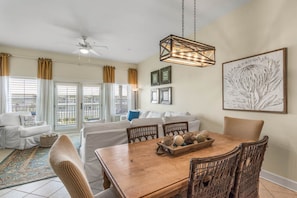 A dining area with a wooden table, wicker chairs, and a chandelier.