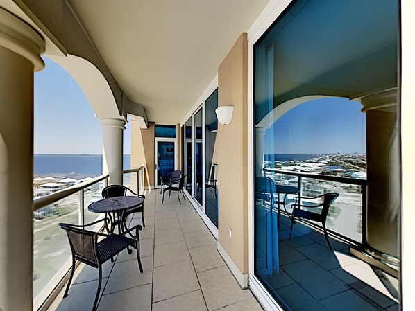 A balcony with a view of the sea and cityscape, featuring a table and chairs. - Portofino Island Resort 5 by Southern Vacation Rentals (Pensacola Beach)