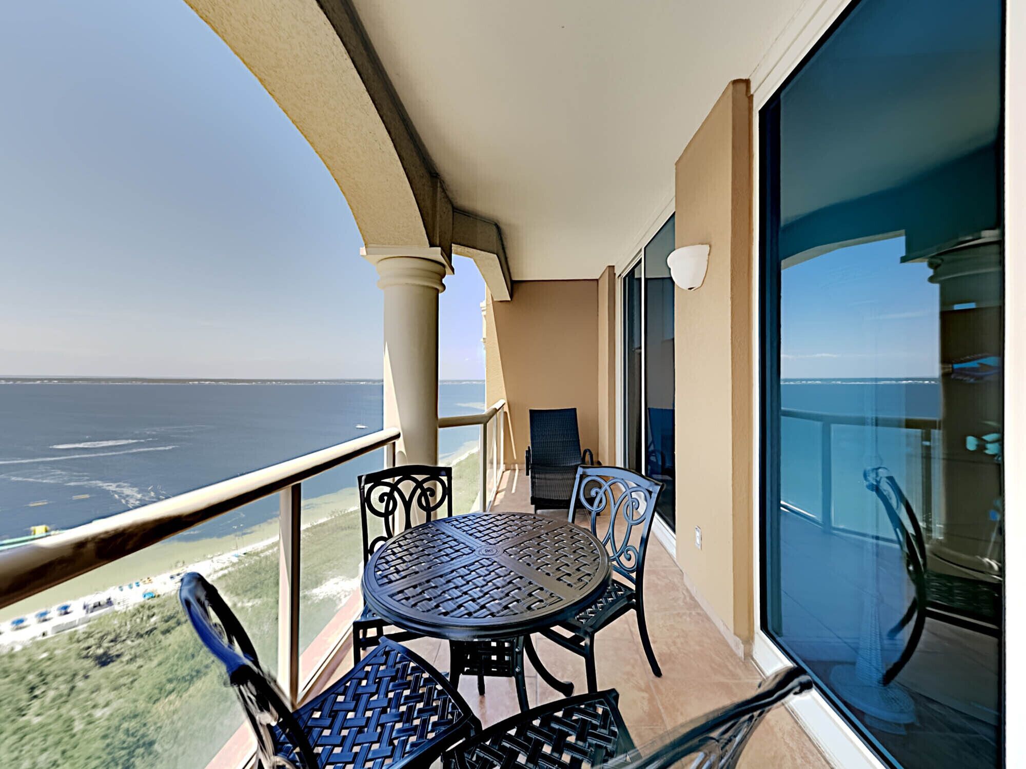 Un balcon avec une table et des chaises, donnant sur une étendue d’eau.