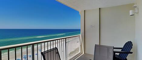 A balcony with a view of the beach and ocean.