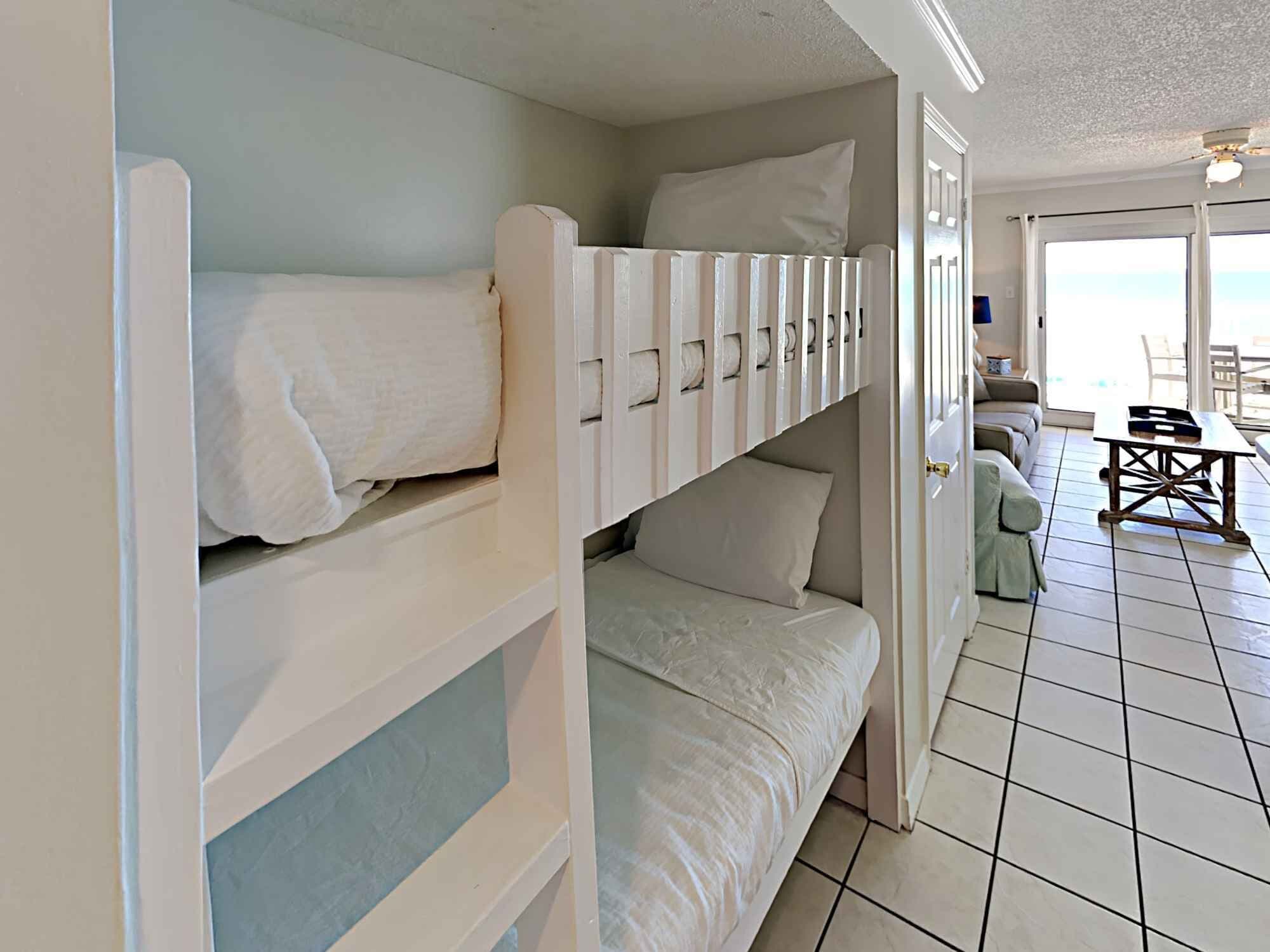 A bunk bed room with a view of the sea through a large window.