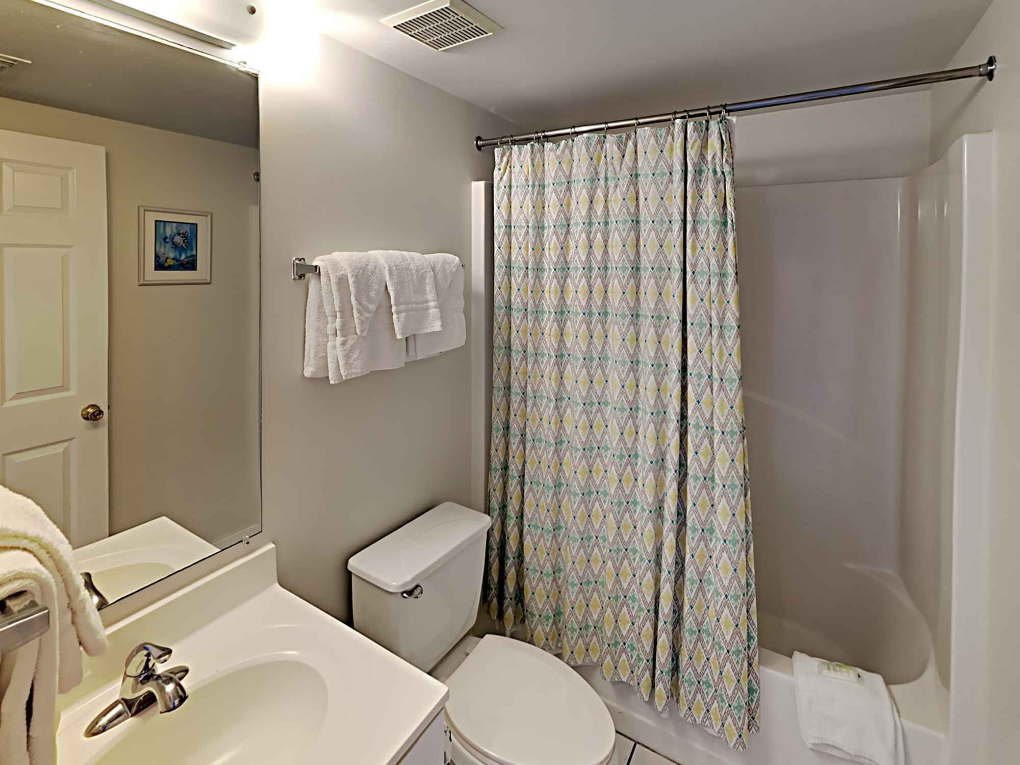 A bathroom with a toilet, sink, and shower curtain.