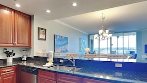 A modern kitchen with wooden cabinets, a granite countertop, and a view to a balcony. - San Anton by Southern Vacation Rentals (Pensacola)