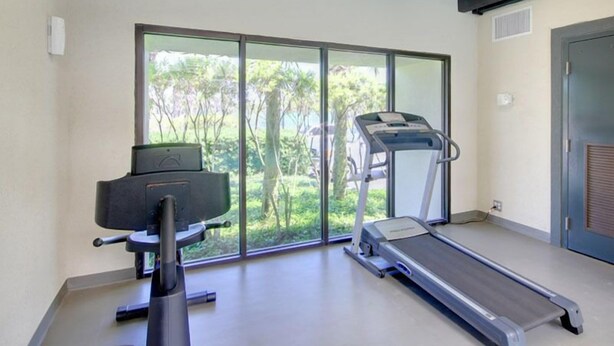 Un gimnasio moderno con cinta de correr, bicicleta estática y banco de pesas.