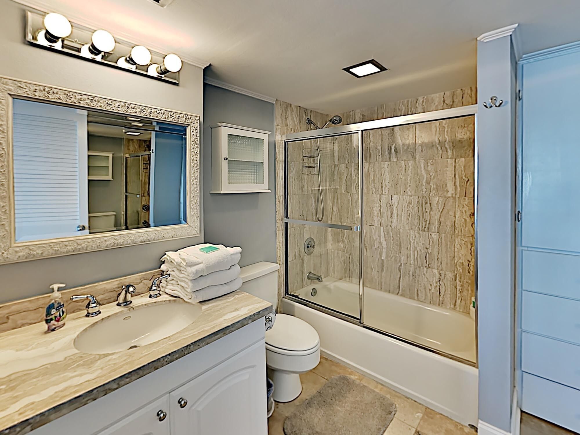 Une salle de bain avec un meuble-lavabo, un évier, un miroir et une douche à l’italienne.