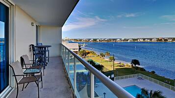 Un balcón con vista al mar, una piscina y una cancha de tenis.