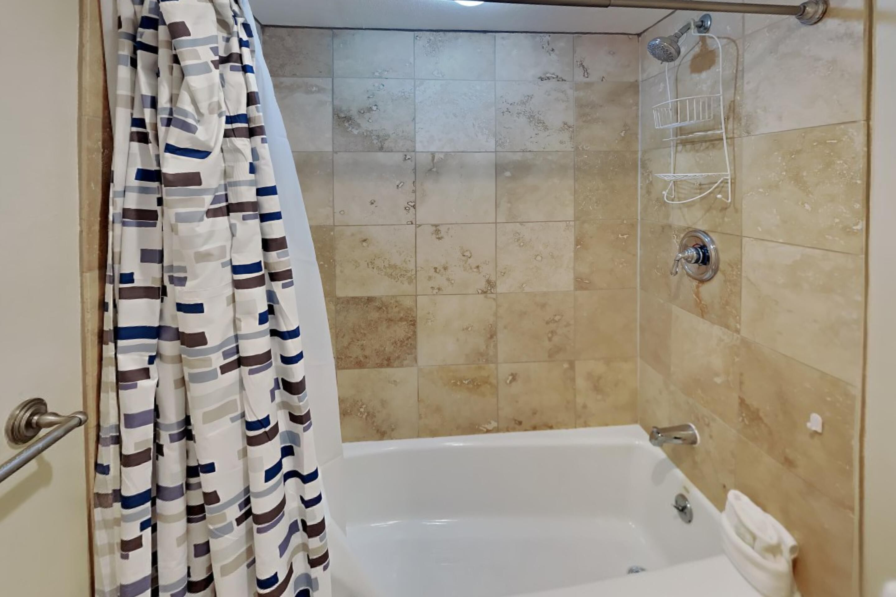 Un bagno con vasca, doccia e pareti piastrellate.