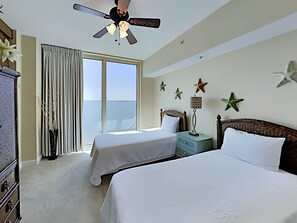 Une chambre d’hôtel avec deux lits, un ventilateur de plafond, une grande fenêtre avec des rideaux et des décorations en forme d’étoiles sur le mur.