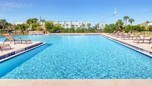 A rectangular swimming pool with clear blue water, surrounded by lounge chairs and a paved deck. - Regency Cabanas by Southern Vacation Rentals (Pensacola Beach)