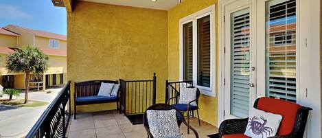 A balcony with a ceiling fan, two chairs, a bench, and a potted plant.