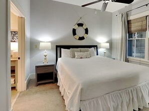 Een netjes ingerichte slaapkamer met een bed, twee nachtkastjes met lampen, een plafondventilator en een wandklok.