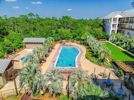 A resort with a large pool surrounded by palm trees and a tennis court.