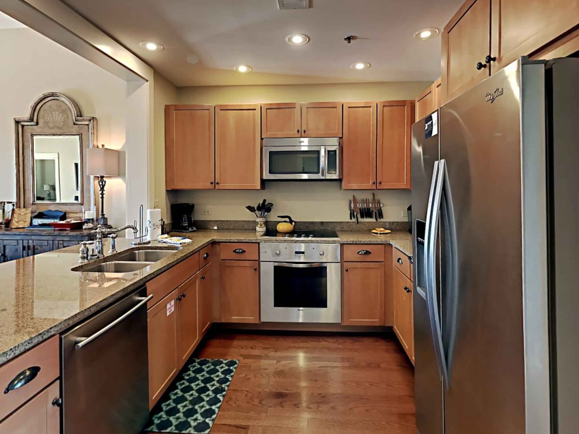 A modern kitchen with wooden cabinets, stainless steel appliances, and a granite countertop.