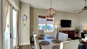 A dining area with a long table, chairs, and a chandelier. - Redfish Village by Southern Vacation Rentals (Santa Rosa Beach)
