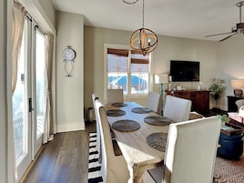 A dining area with a long table, chairs, and a chandelier.