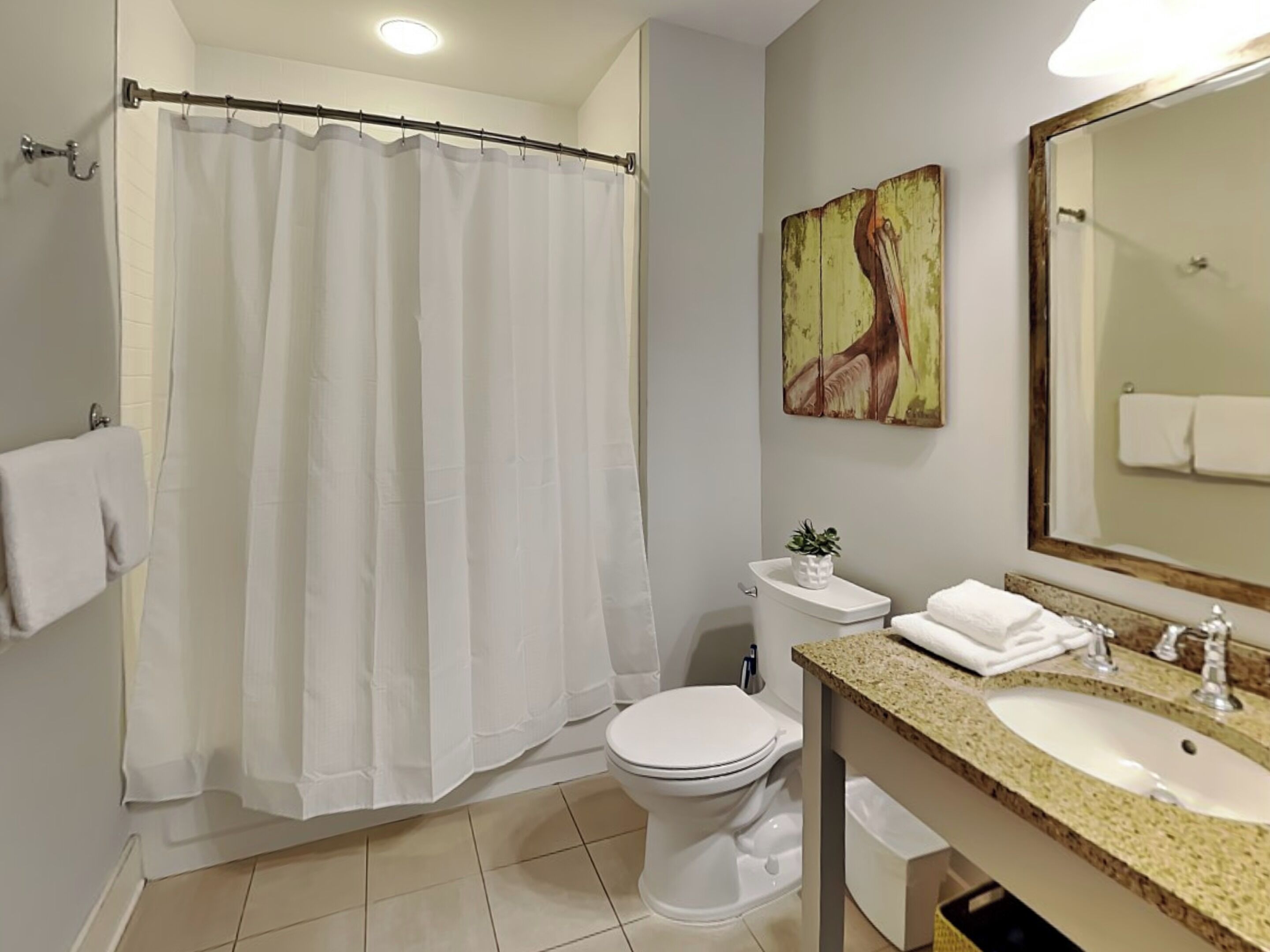 Ein Badezimmer mit Duschvorhang, Toilette, Waschbecken und Spiegel.