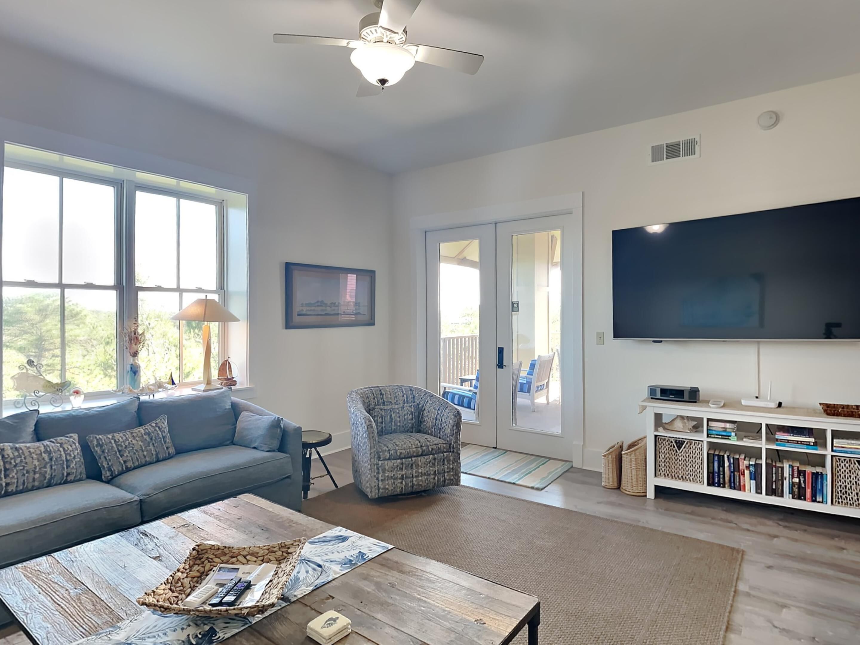 A spacious living room with a sofa, armchair, coffee table, and a TV.