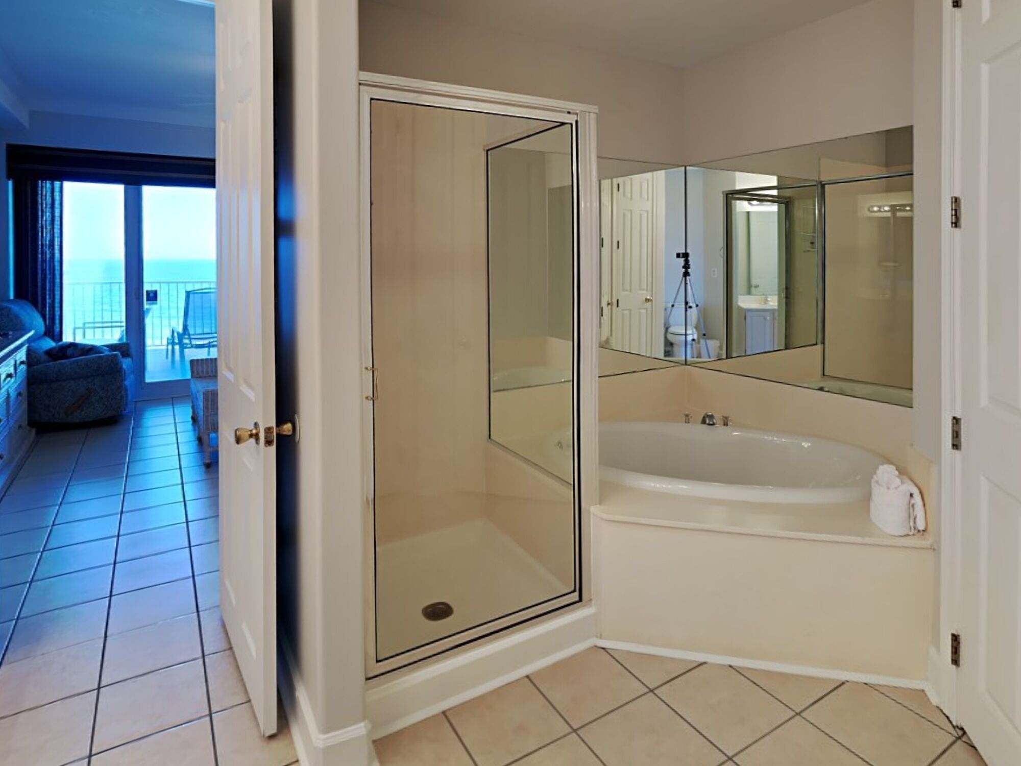 A modern bathroom with a glass-enclosed shower, a large bathtub, and a mirror above it.