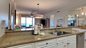 A modern kitchen with granite countertops, stainless steel appliances, and white cabinetry. - Regency Isle by Southern Vacation Rentals (Orange Beach)