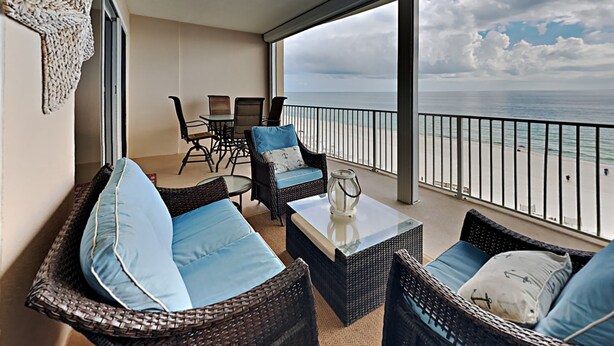 A balcony with wicker furniture, a glass table, and a view of the ocean. - Regency Isle by Southern Vacation Rentals (Orange Beach)
