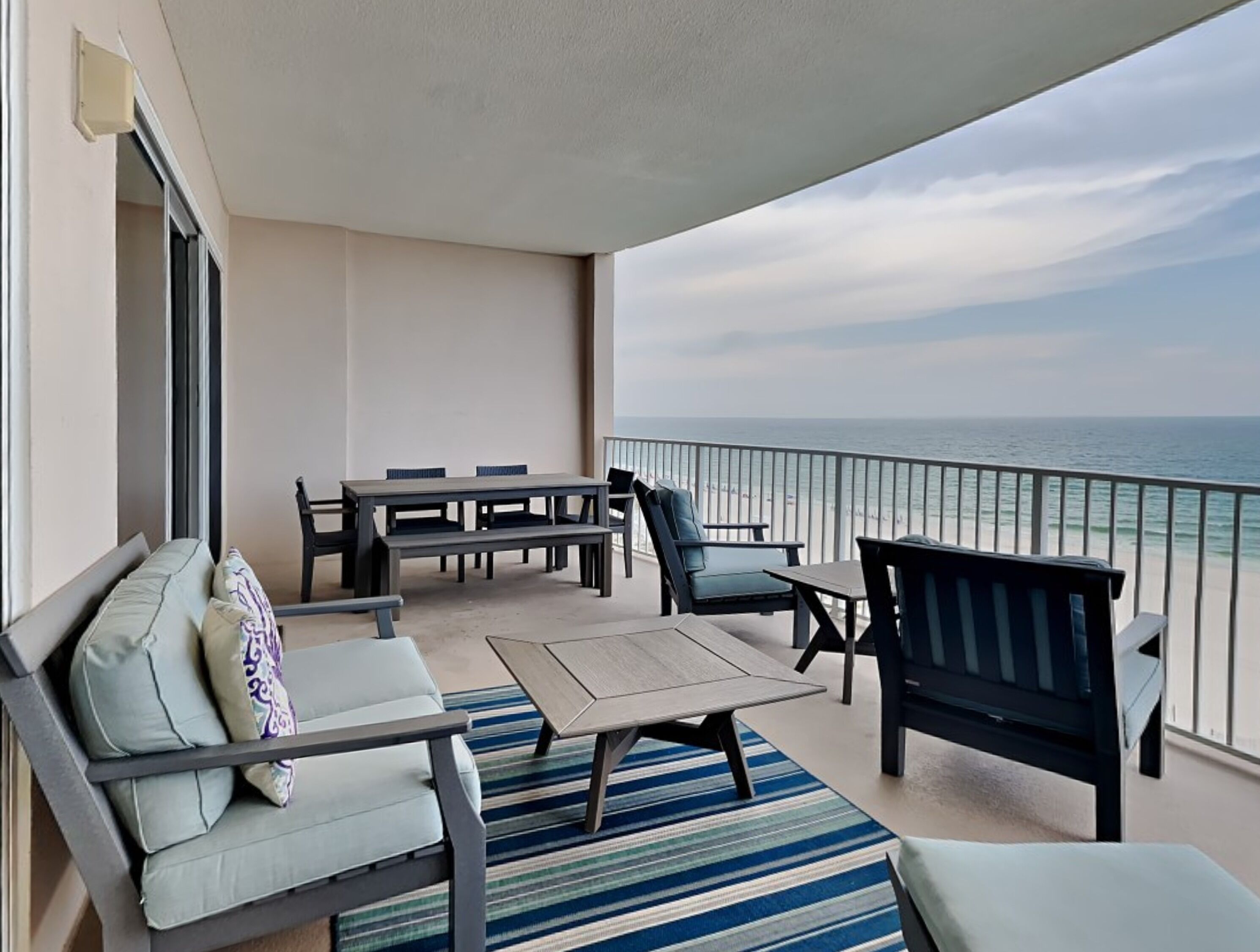 Ein Balkon mit Meerblick, einem Tisch, Stühlen und einer Couch.