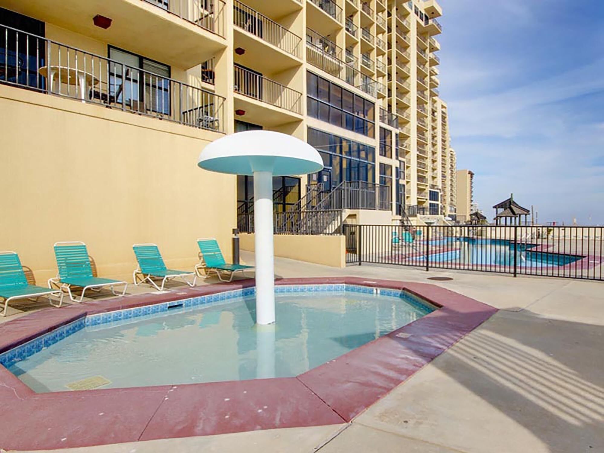 A pool area with lounge chairs and a water feature.