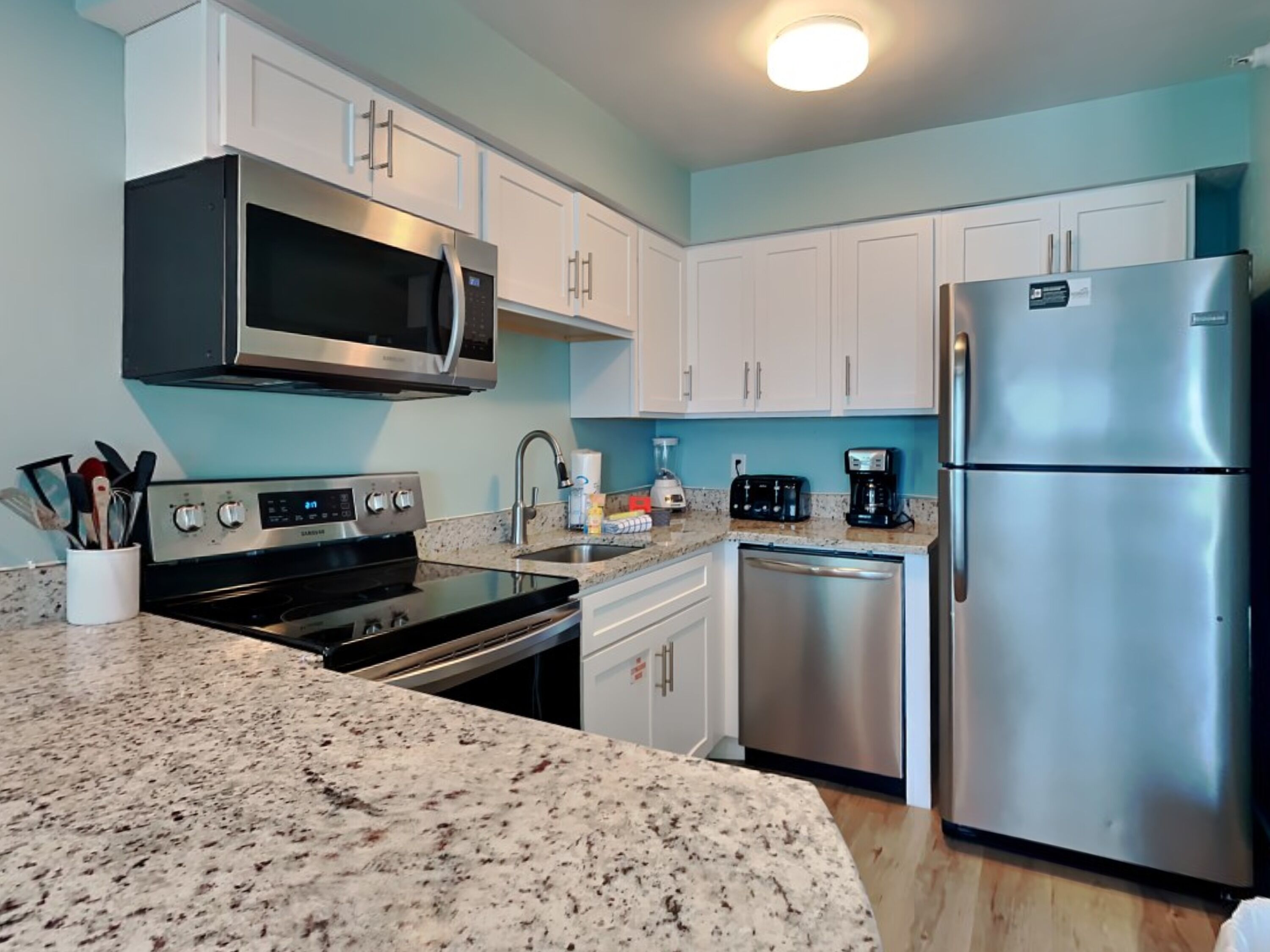 A modern kitchen with stainless steel appliances, granite countertops, and white cabinetry.