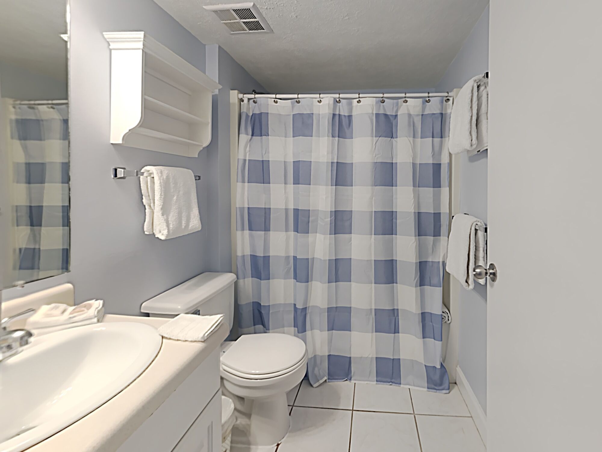 Une salle de bain avec des toilettes blanches, un lavabo et un rideau de douche.