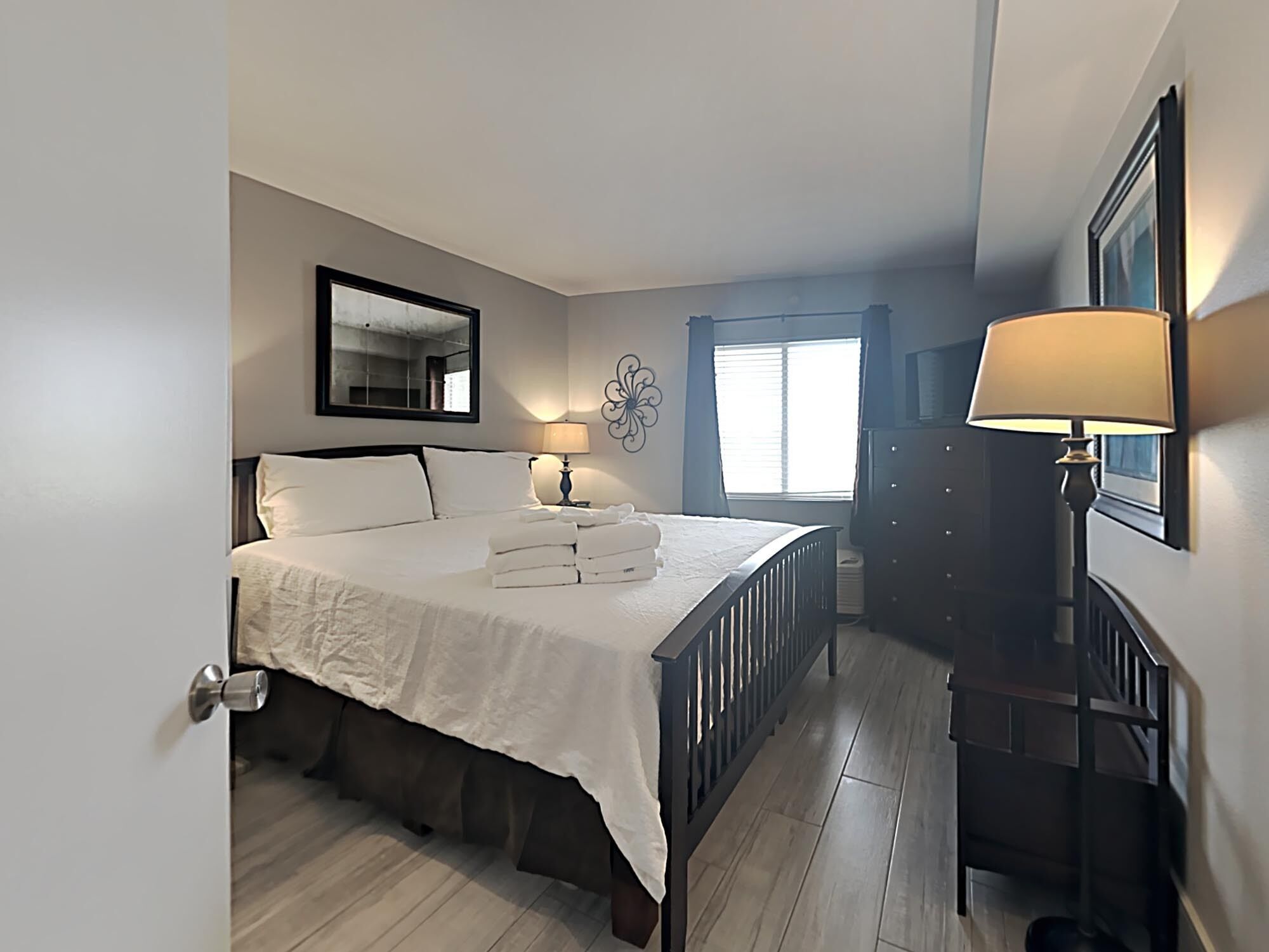 Une chambre à coucher avec un lit, des lampes de chevet, une commode, une fenêtre et un miroir.