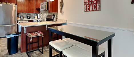 A modern kitchen with wooden cabinets, a central island with bar stools, and a sign on the wall.