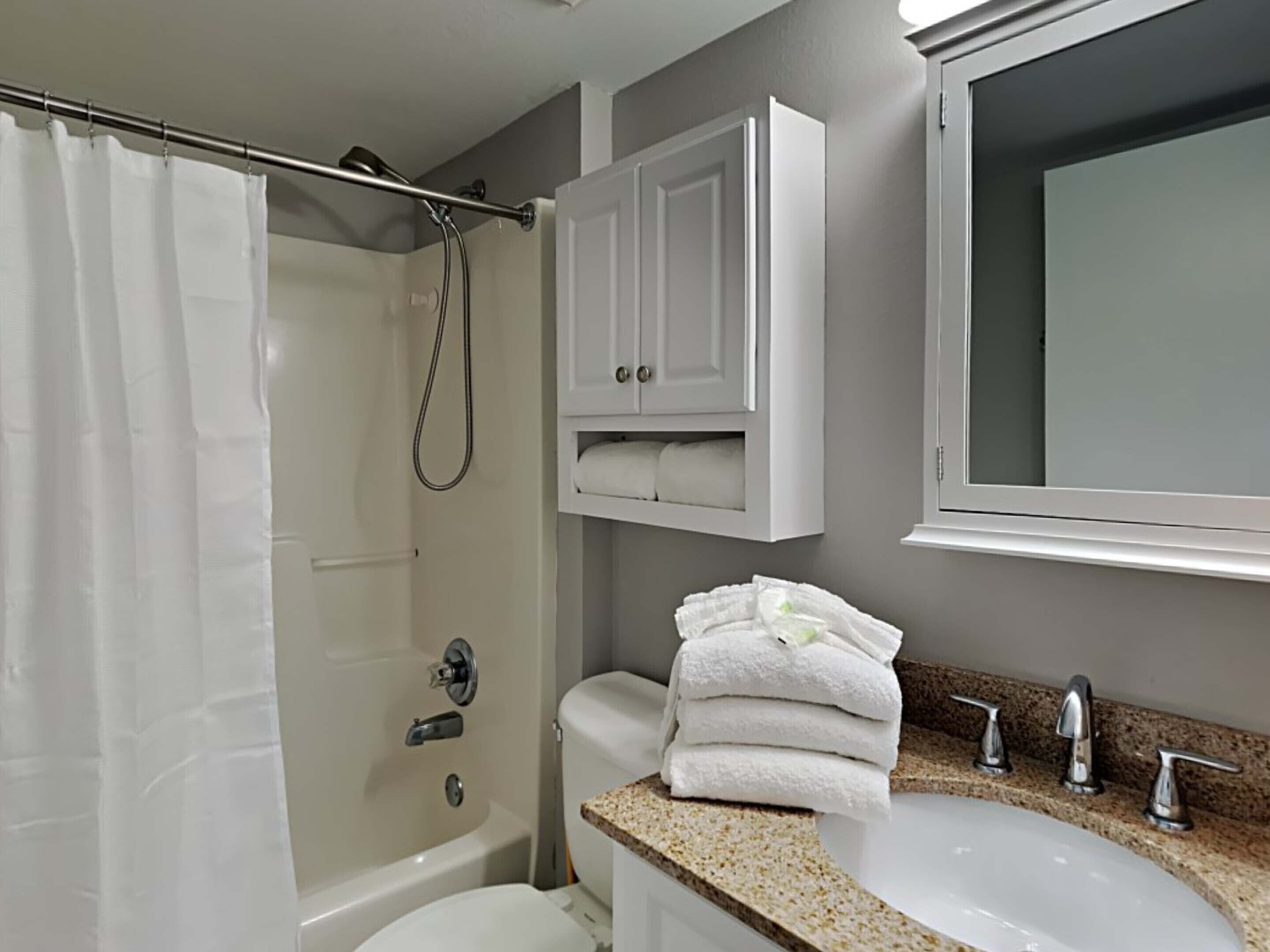 Ein Badezimmer mit Badewanne, Toilette, Waschbecken und einem Schrank darüber.