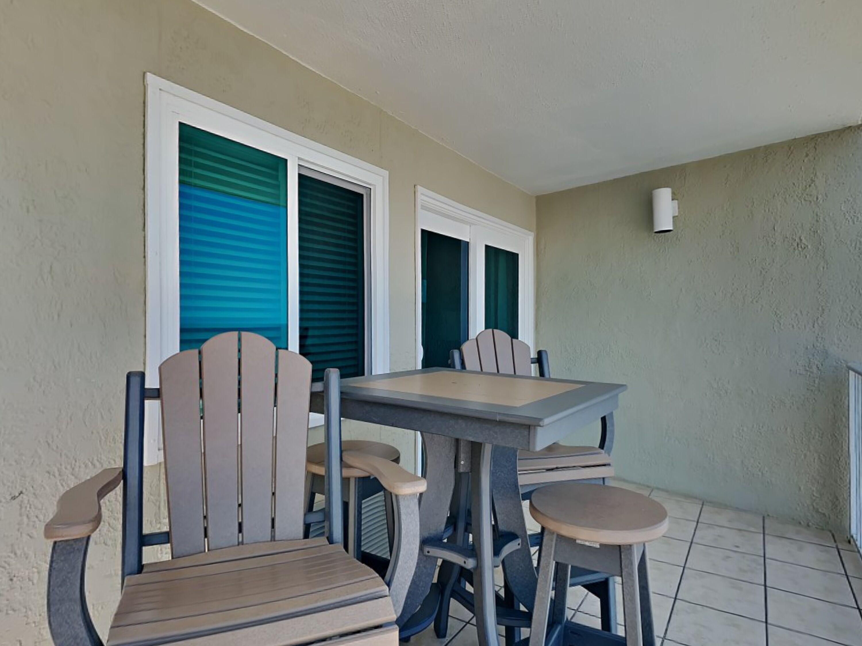 Un balcone con tavolo e sedie, una finestra vista e un lampadario a parete.