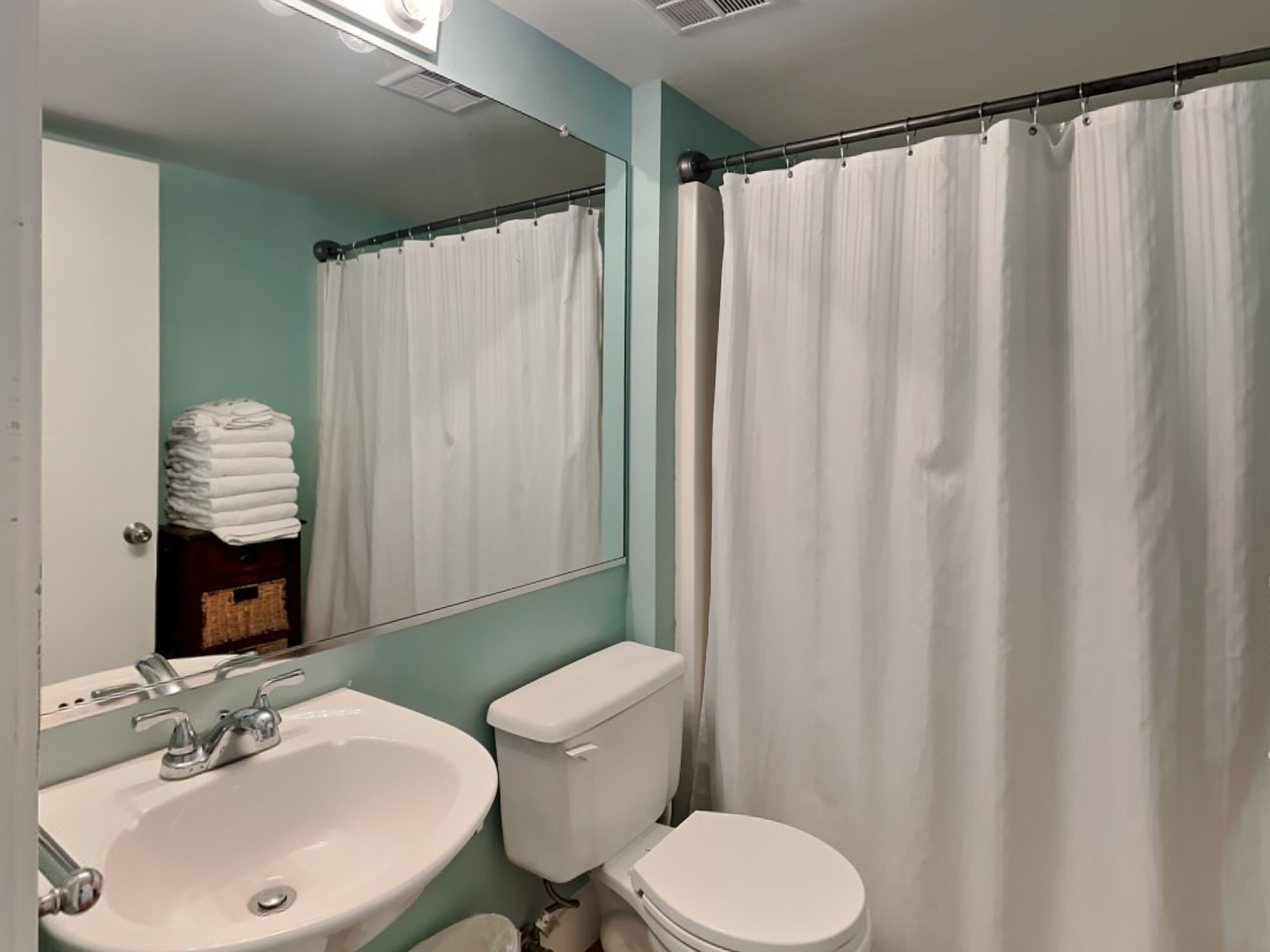Une salle de bain avec un lavabo blanc, des toilettes et un rideau de douche.