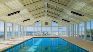 Une piscine intérieure dotée de grandes fenêtres et d’un plafond haut.