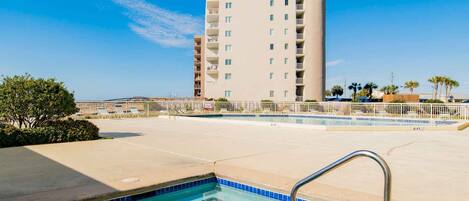 A hotel pool area with a clear view of a tall building in the background.