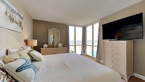Une chambre avec un grand lit, une commode, une télévision et une vue sur l’océan.