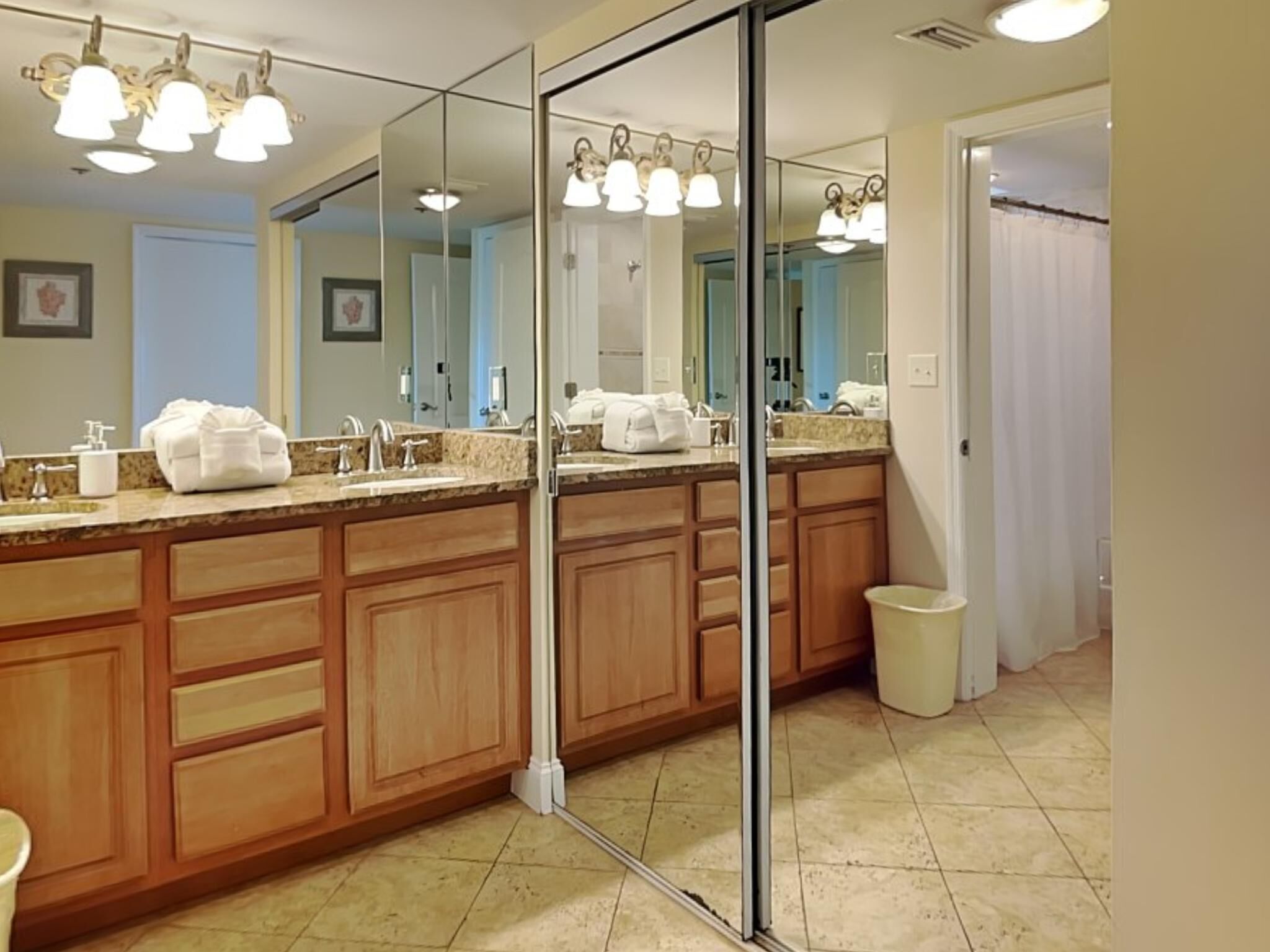 Un baño moderno con un espejo grande, armarios de madera y encimera de mármol.