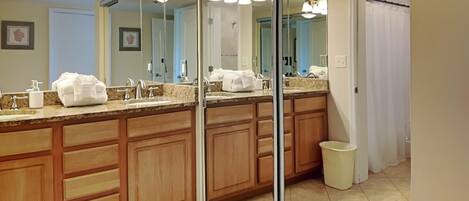 Un baño moderno con un espejo grande, armarios de madera y encimera de mármol.