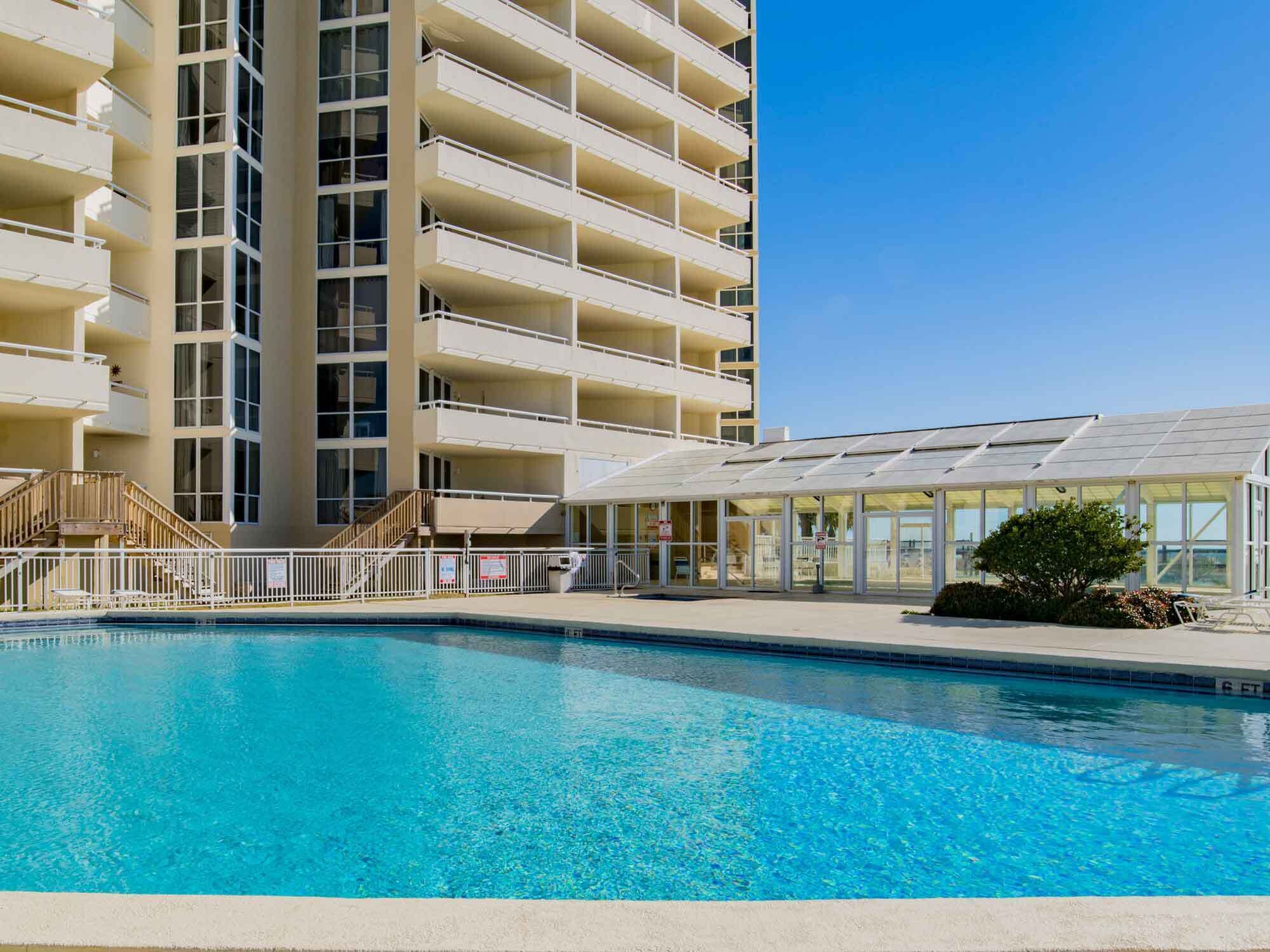 A hotel with a large pool, multiple balconies, and a covered outdoor area.