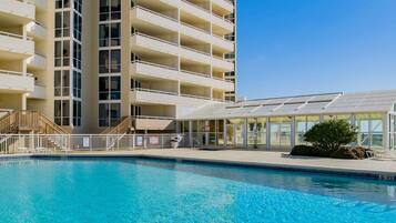 A hotel with a large pool, multiple balconies, and a covered outdoor area.