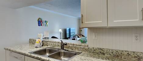 A kitchen with white cabinets, a granite countertop, and stainless steel appliances.