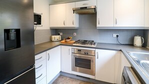 A modern kitchen with stainless steel appliances, white cabinetry, and a built-in oven.