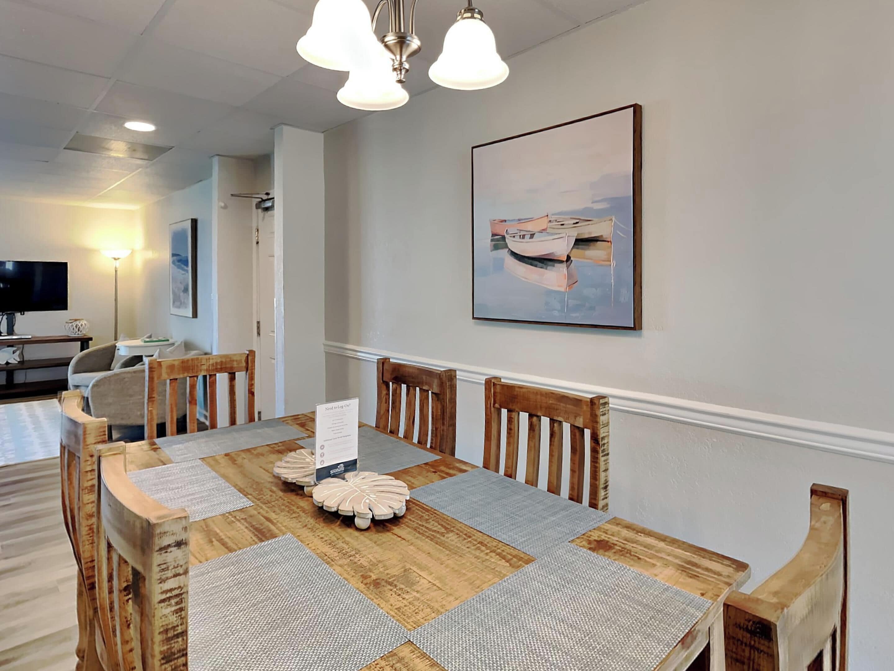 A dining area with a wooden table, chairs, and a painting on the wall.