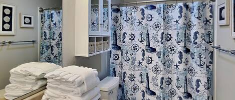 A bathroom with a nautical-themed shower curtain, a sink with a mirror, and a toilet.