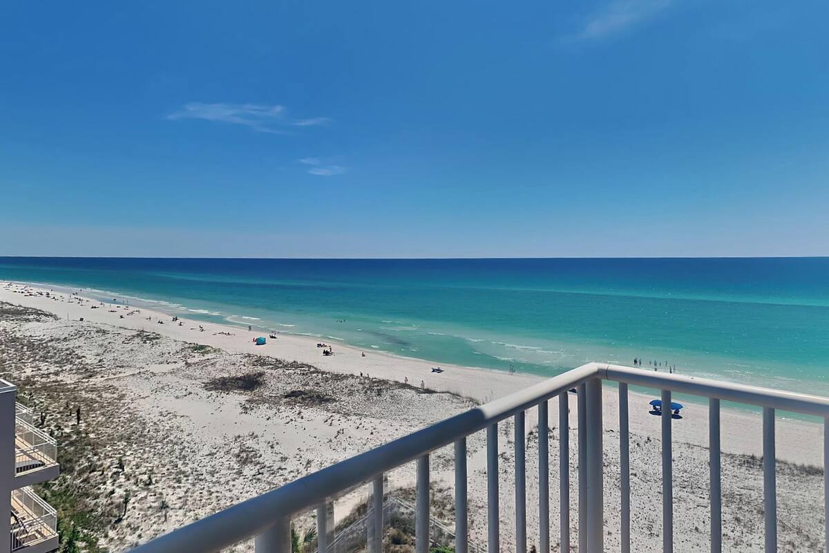 A beach with a clear blue sky, sandy shore, and a view of the ocean.