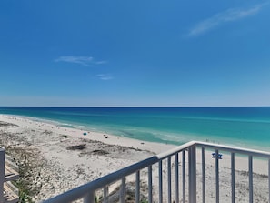 Une plage avec un ciel bleu dégagé, un rivage sablonneux et une vue sur l’océan.