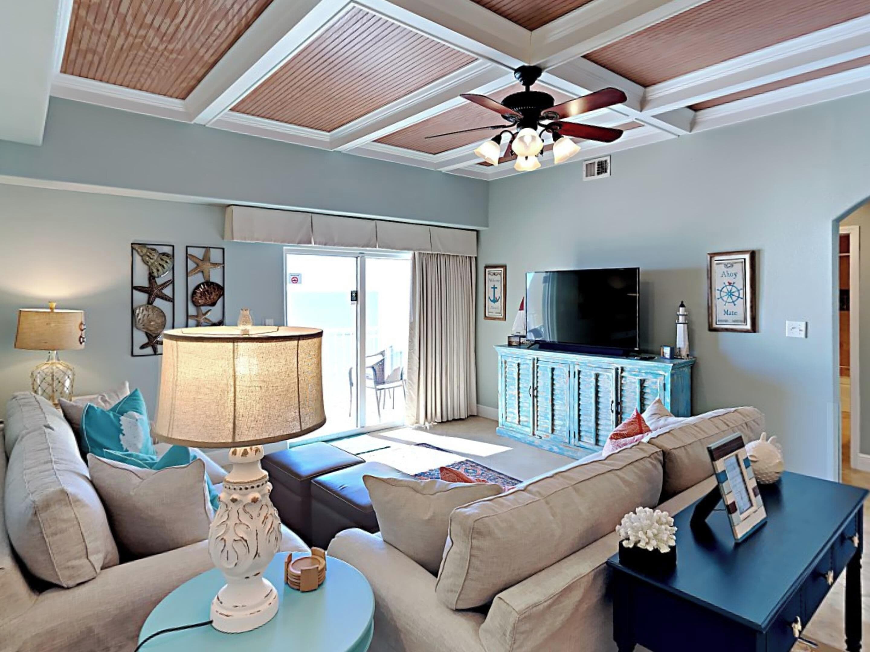 Un salon doté d’un ventilateur de plafond, d’un téléviseur et offrant une vue sur l’extérieur.