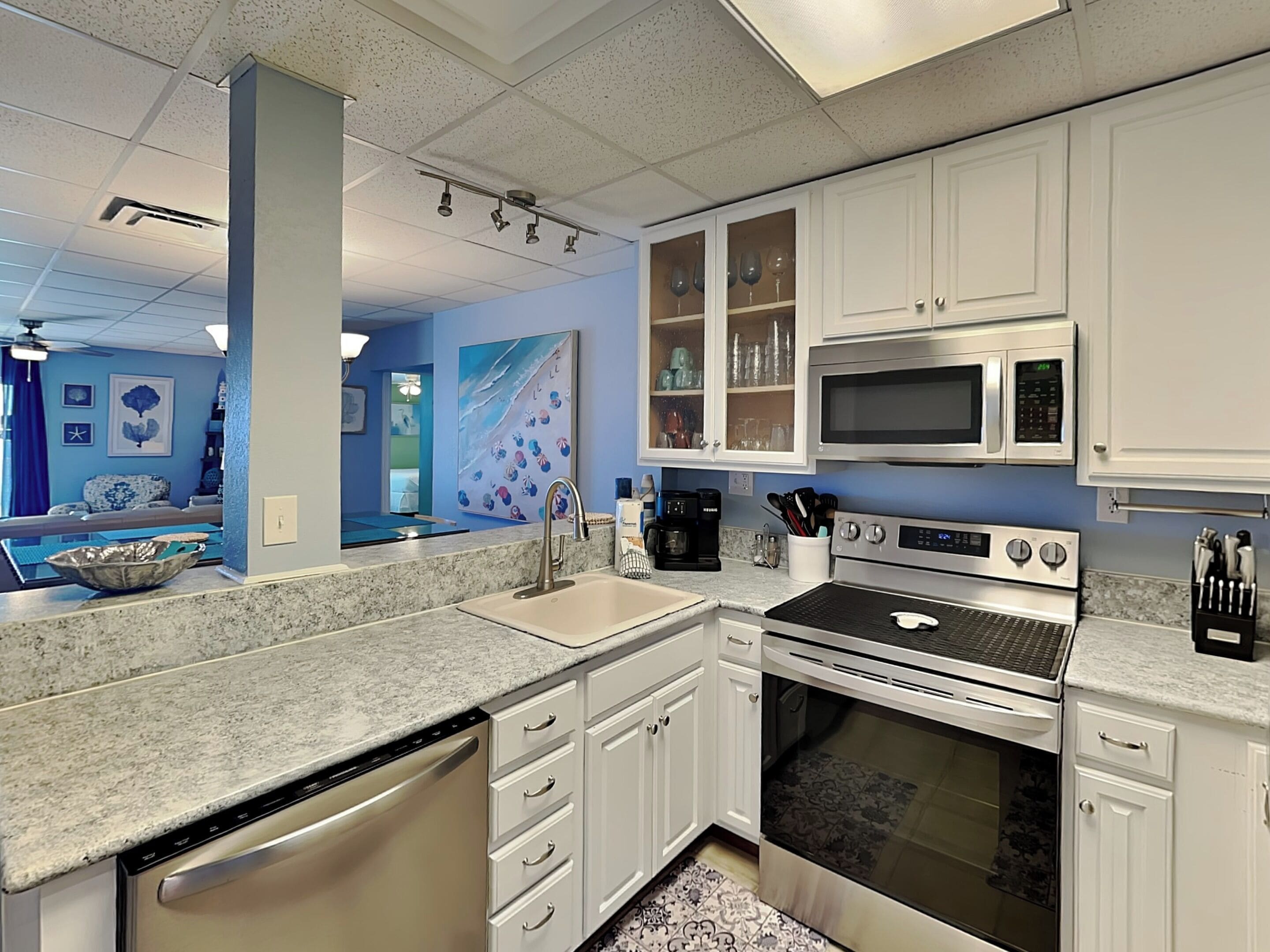 A modern kitchen with white cabinets, stainless steel appliances, and a granite countertop.