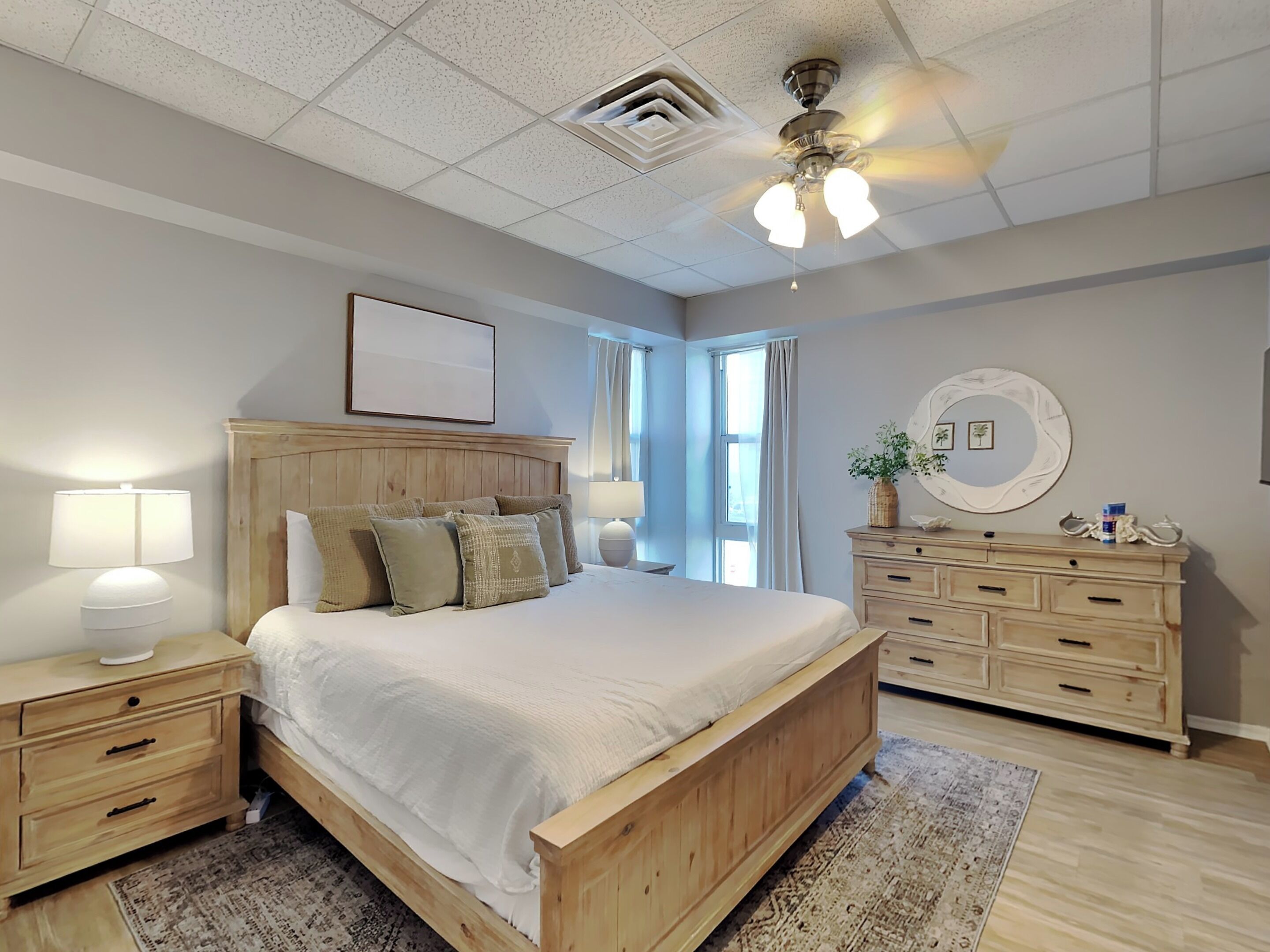 A bedroom with a wooden bed, nightstands, a dresser, and a ceiling fan.