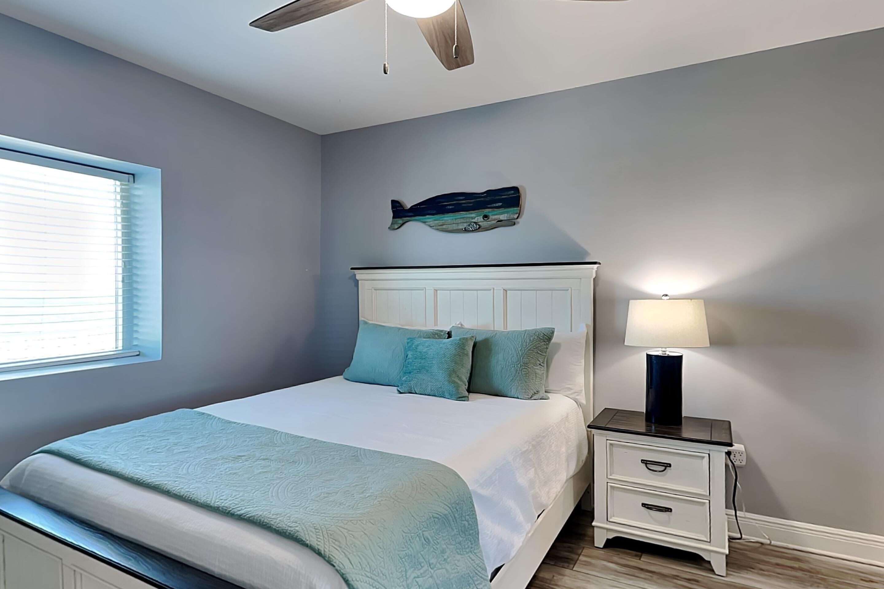 A bedroom with a bed, a nightstand, a lamp, and a wall-mounted fish decoration.